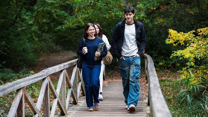 Three students walking together on campus, smiling and talking